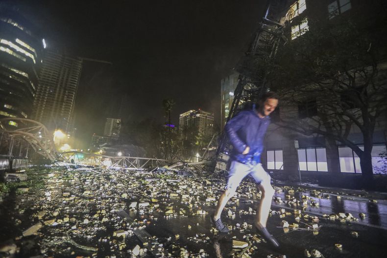 Joe Lindquist, de 32 años, residente en St. Petersburg, camina sobre ladrillos caídos junto a una grúa que colapsó en la 1st Avenue South, cerca de las oficinas del diario Tampa Bay Times, en St. Petersburg, Florida, el 10 de octubre de 2024, tras el paso del huracán Milton por la zona. (Chris Urso/Tampa Bay Times vía AP)
