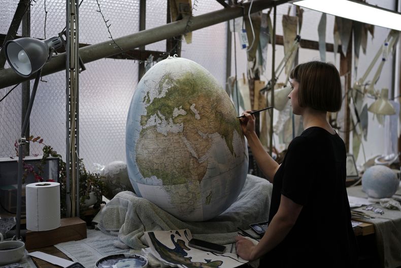 ARCHIVO - Una artista pinta un globo terráqueo en un estudio el 27 de febrero de 2024, en Londres. (AP Foto/Kin Cheung, archivo)