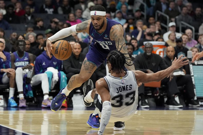 Miles Bridges, alero de los Hornets de Charlotte, comete una falta sobre Tre Jones, de los Spurs de San Antonio, en el partido del viernes 19 de enero de 2024 (AP Foto/Chris Carlson)