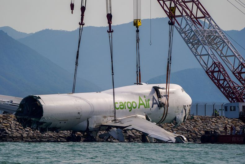 Los restos de un avión de carga que se salió de la pista en el Aeropuerto Internacional de Hong Kong son preparados para su retiro, el domingo 26 de octubre de 2025. (Foto AP/Vernon Yuen)
