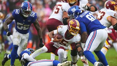 Dru Phillips (22), de los Giants de Nueva York, derriba al quarterback Jayden Daniels (5), de los Commanders de Washington, mientras corría para superar a Darius Alexander (91) y Arvell Reese (52) durante la segunda mitad del partido de la NFL, el domingo 11 de octubre de 2026, en in Landover, Maryland. (AP Foto/Stephanie Scarbrough)