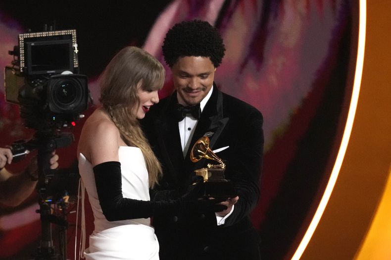 El maestro de ceremonias Trevor Noah, derecha, le entrega el premio a mejor álbum pop vocal para Taylor Swift por Midnights en la 66a entrega anual del Grammy el domingo 4 de febrero de 2024 en Los Ángeles. (Foto AP/Chris Pizzello)