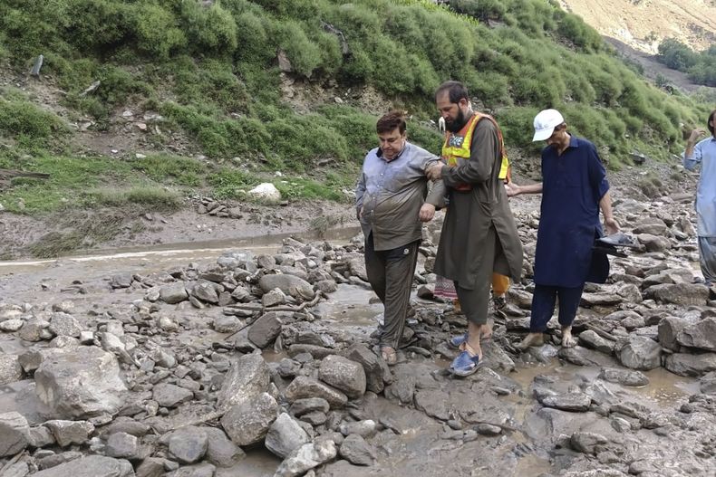En esta imagen publicada por el gobierno de Gilgit Baltistan, rescatistas ayudan a turistas atrapados tras un chaparrón repentino que provocó un deslizamiento de tierra en una autopista cerca del distrito de Chilas, en el norte de Pakistán, el martes 22 de julio de 2025. (Gobierno de Gilgit Baltistan via AP)