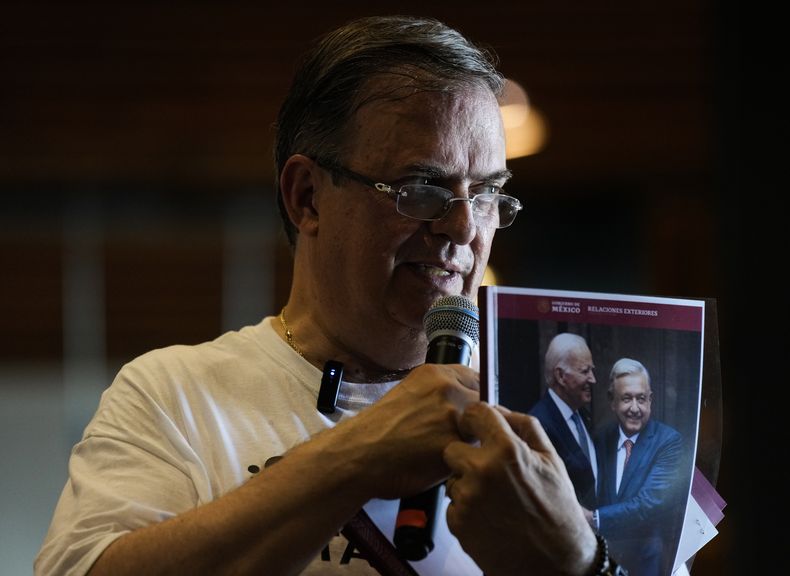 El excanciller mexicano Marcelo Ebrard muestra un reporte de su gestión como secretario de Relaciones Exteriores, presentado con una foto del presidente de México, Andrés Manuel López Obrador, y del mandatario de Estados Unidos, Joe Biden, en una conferencia de prensa en una librería el lunes 12 de junio de 2023, en la Ciudad de México. Ebrard anunció el lunes 19 de junio de 2023 que, de ganar la candidatura de Morena y ser electo presidente, colocaría al hijo del mandatario, Andrés Manuel López Beltrán, a cargo de una nueva secretaría dedicada a la Cuarta Transformación. (AP Foto/Fernando Llano)