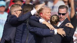 El candidato presidencial republicano, el expresidente Donald Trump, es rodeado por agentes del Servicio Secreto de Estados Unidos mientras es ayudado a bajar de la tarima en un mitin de campaña en Butler, Pensilvania, el sábado 13 de julio de 2024. (Foto AP/Gene J. Puskar)