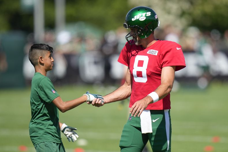 Aaron Rodgers, derecha, quarterback de los Jets de Nueva York, saluda a un niño durante la sesión de entrenamiento del equipo en las instalaciones del equipo en Florham Park, Nueva Jersey, el domingo 30 de julio de 2023. (AP Foto/Seth Wenig)