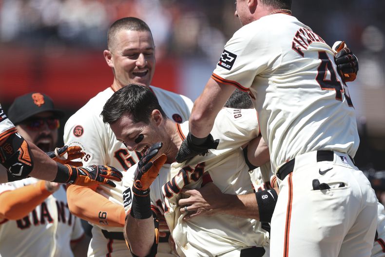 Mike Yastrzemski de los Gigantes de San Francisco (centro) celebra luego de conectar un triple decisivo ante los Mellizos de Minnesota, en el juego de béisbol en San Francisco, el domingo 14 de julio de 2024. (AP Foto/Kavin Mistry)