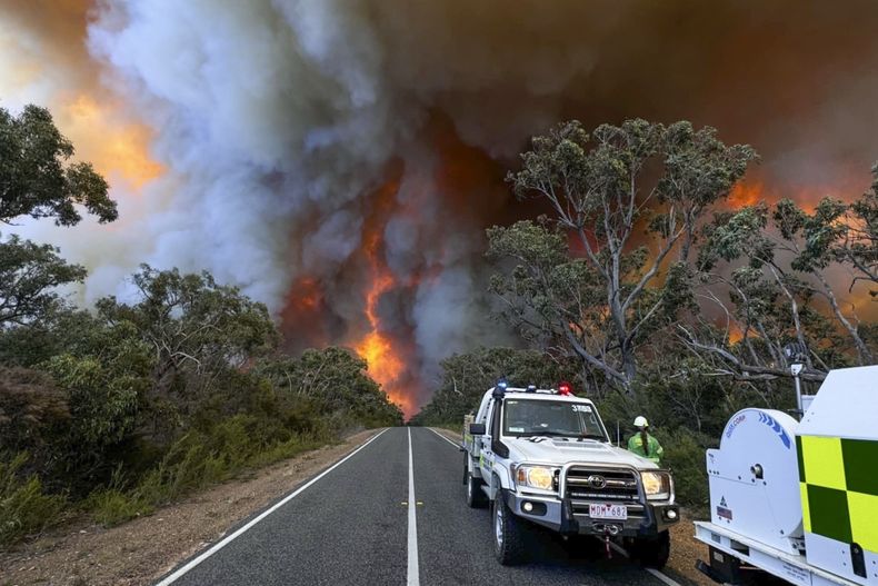 En esta foto, distribuida por el Centro de Control Estatal, personal del departamento de bomberos del condado observa las llamas y el humo de un incendio fuera de control en el parque nacional Grampians, en el estado de Victoria, Australia, el 20 de diciembre de 2024. (Centro de Control Estatal vía AP)