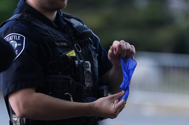 Un policía coloca un casquillo en un guante de goma tras recibirlo de una persona que lo encontró, después de un tiroteo en el Seattle Center durante el festival gastronómico Bite of Seattle, el lunes 27 de julio de 2026, en Seattle. (AP Foto/Lindsey Wasson)