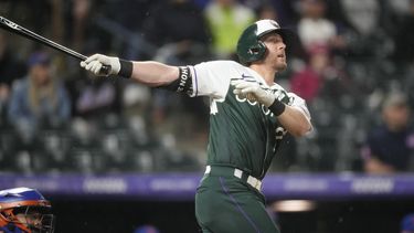 Ryan McMahon, de los Rockies de Colorado, observa la pelota al conectar un jonrón de dos carreras en el juego del sábado 27 de mayo de 2023 ante los Mets de Nueva York (AP Foto/David Zalubowski)
