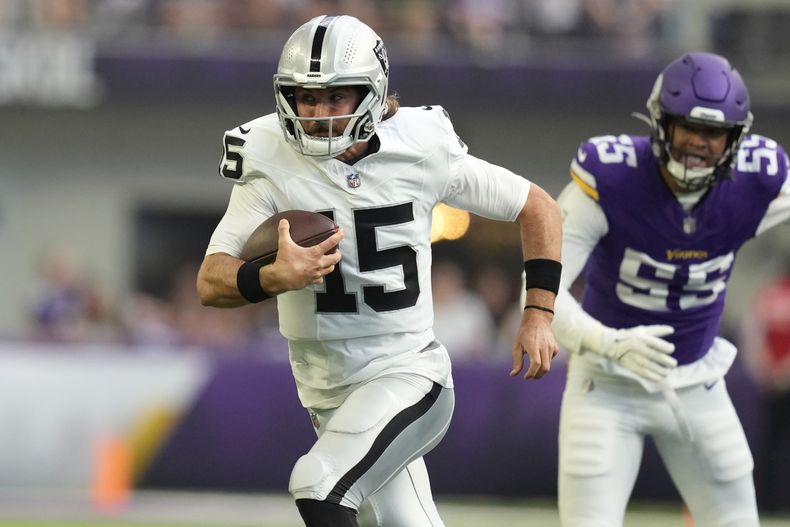 El quarterback de los Raiders de Las Vegas, Gardner Minshew II (15), supera al apoyador de los Vikings de Minnesota, Andre Carter II (55), durante la primera mitad de un partido de fútbol americano de la NFL, el sábado 10 de agosto de 2024, en Minneapolis. (AP Foto/Charlie Neibergall)