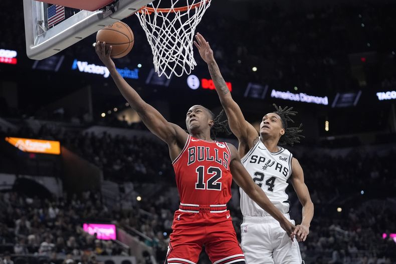 Ayo Dosunmu, base de los Bulls de Chicago, anota frente a Devin Vassell, de los Spurs de San Antonio, en el partido del sábado 13 de enero de 2024 (AP Foto/Eric Gay)