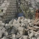 Residentes, junto a la pared derrumbada de una casa dañada en un ataque en la localidad de Patan, en la provincia de Kunar, en el este de Afganistán, el 21 de septiembre de 2026. (AP Foto/Shafiullah Kakar)