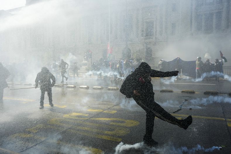 ARCHIVO - Un manifestante da una patada a una bomba de gas lacrimógeno lanzada por la policía en una marcha para reclamar territorios autónomos para pueblos indígenas de Chile y la liberación de detenidos a favor de los mapuches, en Santiago, Chile, el 13 de octubre de 2024. (AP Foto/Esteban Felix, Archivo)