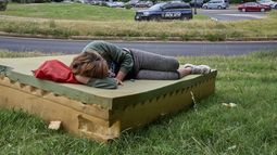 Stephanie W., de 28 años, que no tiene hogar, descansa en un colchón de espuma mientras pasa un vehículo de la Policía de Parques de EEUU, el 13 de agosto de 2025, en el noroeste de Washington, cerca del Kennedy Center. (AP Foto/Jacquelyn Martin)