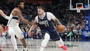 Luka Doncic (77), de los Mavericks de Dallas, lleva el balón ante la presión de Marvin Bagley III (35), de los Wizards de Washington, durante la primera mitad del juego de baloncesto de la NBA en Dallas, el lunes 12 de febrero de 2024. (AP Foto/LM Otero)