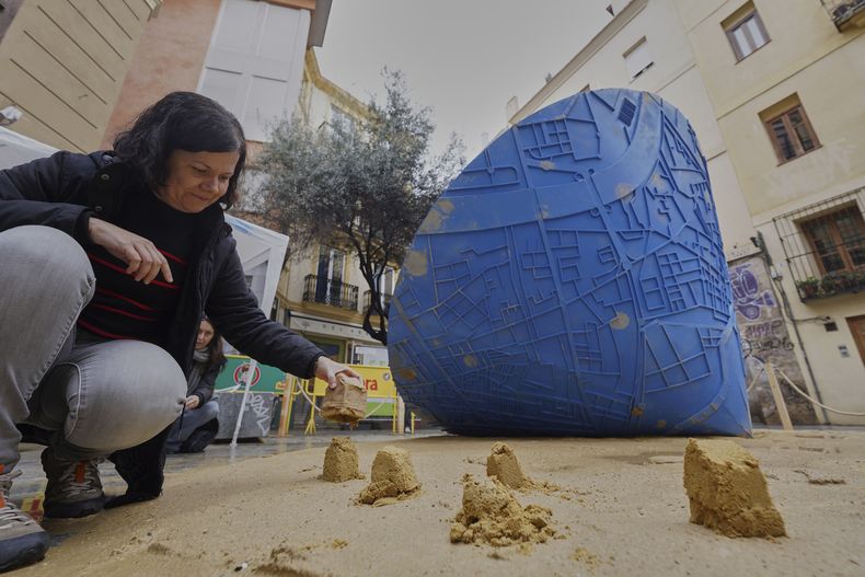 Una asistente coloca moldes de arena cerca de una escultura en forma de cono que, al girar, dibuja en el piso un mapa de las ciudades afectadas por las inundaciones, en el festival de las Fallas en Valencia, España, el miércoles 19 de marzo de 2025. Cinco meses después de las letales inundaciones que arrasaron Valencia, la ciudad española tendrá su mayor celebración del año: Las Fallas. Las esculturas se elaboraron con restos de las casas de las personas y se burlan de políticos acusados de manejar erróneamente la catástrofe. (AP Foto/Alberto Saiz)