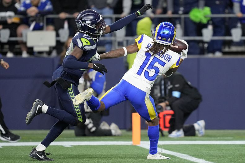 Demarcus Robinson (15), wide receiver de los Rams de Los Ángeles, atrapa un pase con una mano ante la cobertura del cornerback Riq Woolen, de los Seahawks de Seattle, durante el tiempo extra del partido de la NFL, el domingo 3 de noviembre de 2024, en Seattle. (AP Foto/Stephen Brashear)