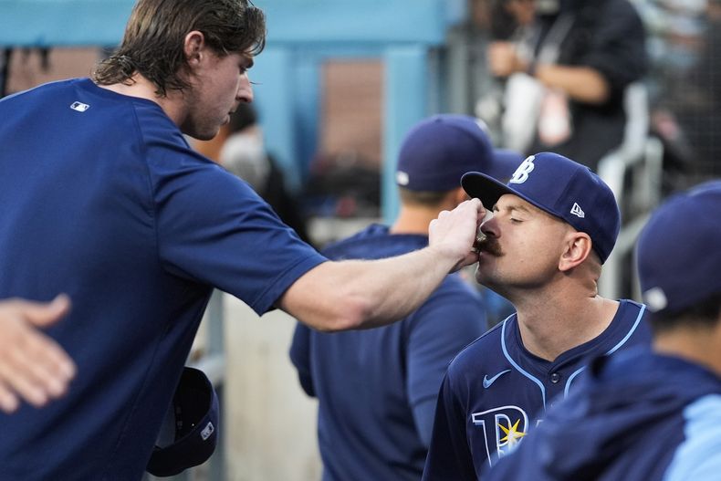 ARCHIVO - Ryan Pepiot, de los Rays de Tampa Bay, izquierda, ajusta el bigote del lanzador abridor Tyler Alexander antes de un partido de béisbol contra los Dodgers de Los Ángeles en Los Ángeles, el viernes 23 de agosto de 2024. (Foto AP/Ashley Landis, archivo)
