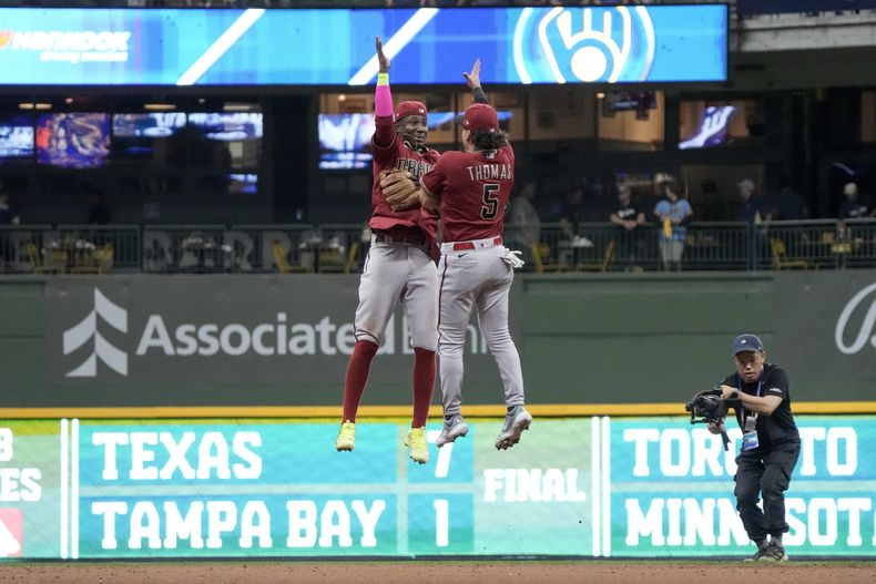 El dominicano Geraldo Perdomo y Alek Thomas (5) de los Diamondbacks de Ariazona celebran luego del Juego 2 en la serie de comodín de la Liga Nacional ante los Cerveceros de Milwaukee, en Milwaukee. Miércoles 4 de octubre de 2023. (AP Foto/Morry Gash)