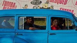Personas en un taxi frente a un cartel contra el bloqueo estadounidense de Cuba, en La Habana, el 28 de abril del 2026. (AP foto/Ramon Espinosa)