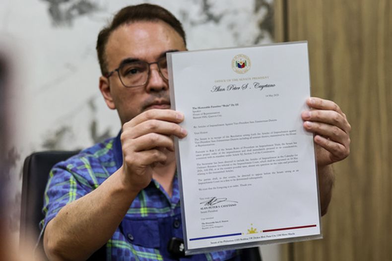 El presidente del Senado filipino Alan Peter Cayetano sujeta una carta dirigida al presidente de la Cámara de Diputados Faustino Dy III, reconociendo recibo de la resolución sobre artículos de juicio político contra la vicepresidenta Sara Duterte, en el Senado, en Pasay City, el 14 de mayo del 2026. (AP foto/Gerard Carreon)