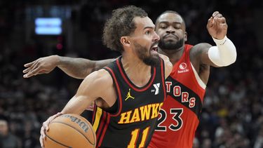 Trae Young (11), de los Hawks de Atlanta, se enfila con el balón hacia la canasta, dejando atrás la marca defensiva de Jamal Shead (23), de los Raptor de Toronto, en el juego de baloncesto de la NBA del domingo 29 de diciembre de 2024, en Toronto. (Frank Gunn/The Canadian Press vía AP)