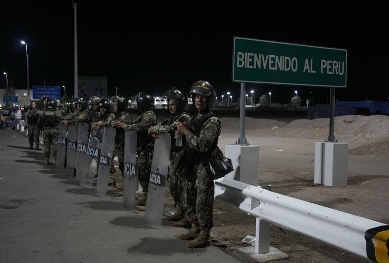 La policía peruana antimotines hace guardia en el frontera entre Chile y Perú el jueves 27 de abril de 2023. Una crisis migratoria en la frontera entre Chile y Perú se intensificó con la llegada de cientos de personas, en su mayoría venezolanas, que quedaron varadas en la zona limítrofe, al no poder cruzar a Perú desde Chile en su ruta para regresar a sus países de origen por el impedimento de entrar a territorio peruano al carecer de documentación. (AP Foto/Martín Mejía)