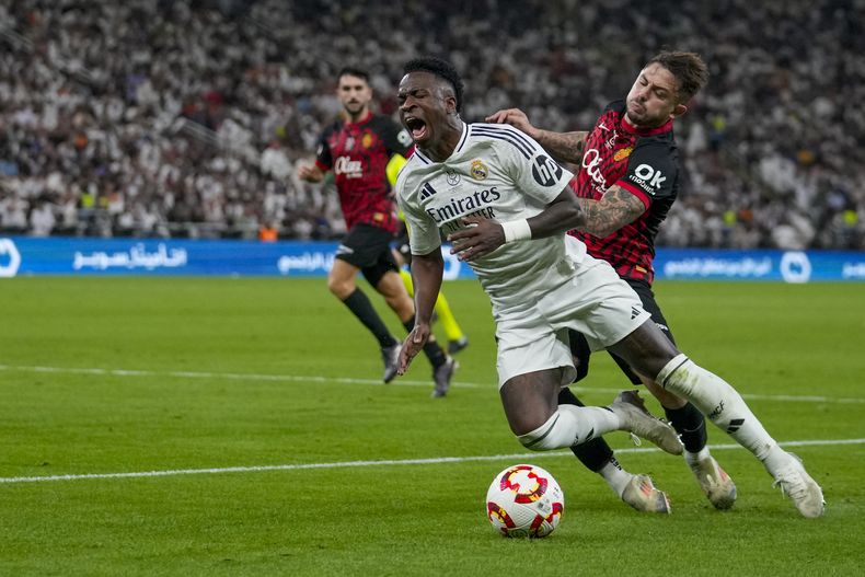Vinicius del Real Madrid cae ante la marca de Pablo Maffeo del Mallorca durante la semifinal de la Supercopa de España, el jueves 9 de enero de 2025, en Yeda, Arabia Saudí. (AP Foto/Altaf Qadri)