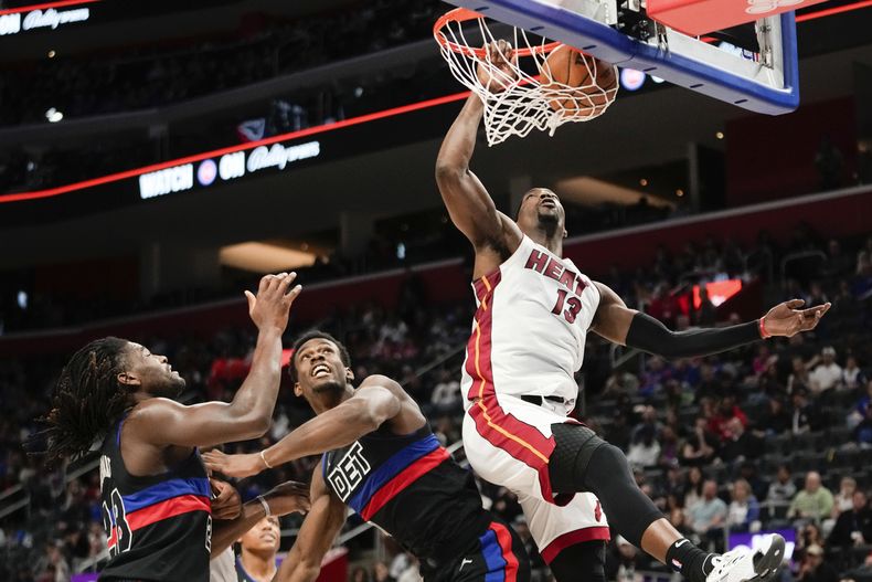 Bam Adebayo (13), del Heat de Miami, clava el balón superando a Isaiah Stewart (28) y Jalen Duren (0) en la primera mitad del juego de baloncesto de la NBA, en Detroit, el viernes 15 de marzo de 2024. (AP Foto/Paul Sancya)
