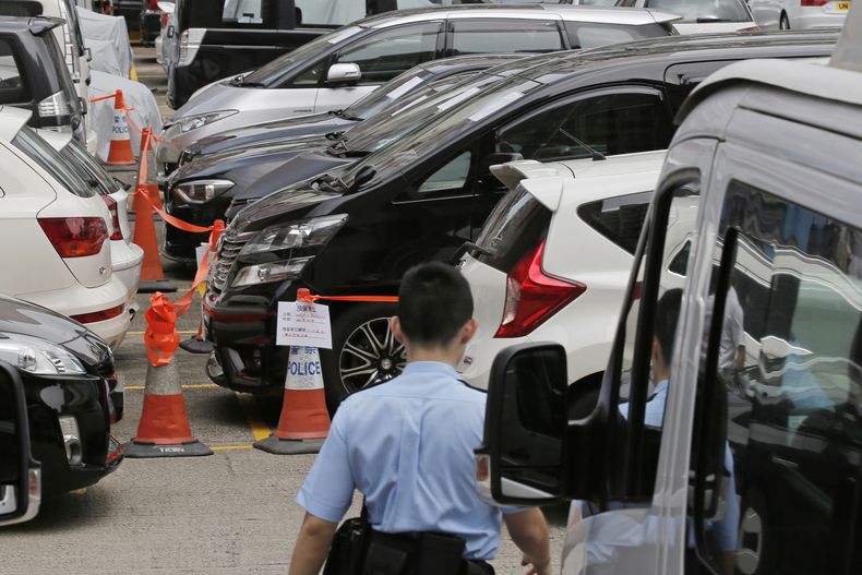 ARCHIVO - Vehículos confiscados destinados al servicio Uber, en el centro, están estacionados detrás de un cordón policial en una comisaría de Hong Kong, el martes 23 de mayo de 2017. (AP Foto/Kin Cheung, archivo)