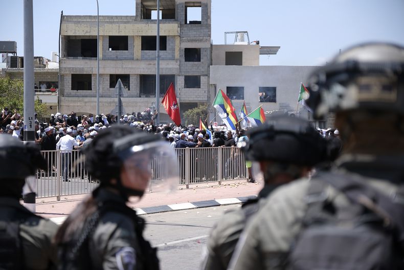 Policías antimotines con equipo antidisturbios se ven junto a manifestantes drusos durante una marcha contra la construcción de un parque eólico en los Altos del Golán, el miércoles 21 de junio de 2023. (AP Foto/Fadi Amun)