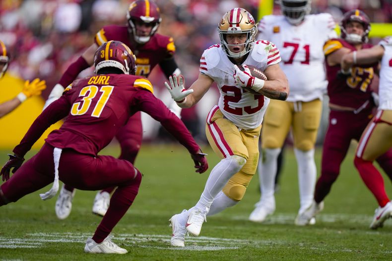 El corredor de los 49ers de San Francisco Christian McCaffrey corre mientras el safety Kamren Curl (31) de los Commanders de Washington intenta detenerlo, durante la primera mitad del juego de la NFL, el domingo 31 de diciembre de 2023, en Landover, Maryland. (AP Foto/Mark Schiefelbein)