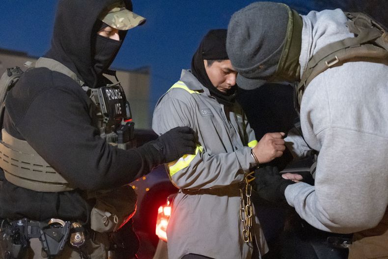 Agentes del Servicio de Control de Inmigración y Aduanas de Estados Unidos utilizan una cadena para manejar mejor a una persona que ya trae esposas, el lunes 27 de enero de 2025, en Silver Spring, Maryland. (AP Foto/Alex Brandon)