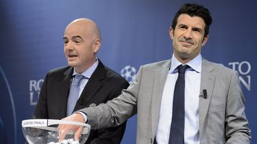 americateve | Luis Figo se apresta a sacar una bola del bollillero durante el sorteo de los cuartos de final de la Liga de Campeones el 21 de marzo del 2014 en Nyon, Suiza. A su lado aparece el secretario general de la UEFA Gianni Infantino. (AP Photo/Keystone,Laurent