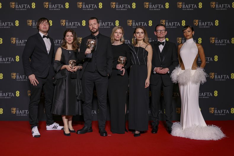 El fotógrafo de The Associated Press Evgeniy Maloletka, de izquierda a derecha, la editora y productora de Frontline de PBS Raney Aronson, el director, productor y periodista de AP Mstyslav Chernov, la editora y productora Michelle Mizner, la productora de campo y videoperiodista de AP Vasilisa Stepanenko, el productor y vicepresidente de AP y director de producción Derl McCrudden, ganadores del premio a mejor documental por 20 Days in Mariupol, posan junto a Taylor Russell en la 77a entrega de los Premios de la Academia Británica de Cine (BAFTA) en Londres el domingo 18 de febrero de 2024. (Foto Vianney Le Caer/Invision/AP)