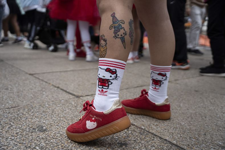 Una fan del personaje japonés Hello Kitty muestra tatuajes y zapatos temáticos después de cruzar la línea de meta en una carrera durante la celebración del 50 aniversario del personaje, en la Ciudad de México, el domingo 13 de octubre de 2024. (Foto AP/Aurea Del Rosario)