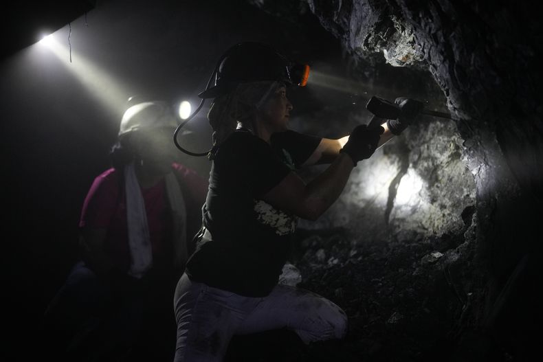 Con un casco con linterna, Margot Ávila, de 45 años, utiliza un martillo industrial para perforar las rocas en un túnel de una mina informal cerca de la población de Coscuez, Colombia, el miércoles 28 de febrero de 2024. La tierra y las rocas que extraen de las paredes se llevan en carros afuera de la mina, y después son separadas y lavadas en busca de esmeraldas. (AP Foto/Fernando Vergara)