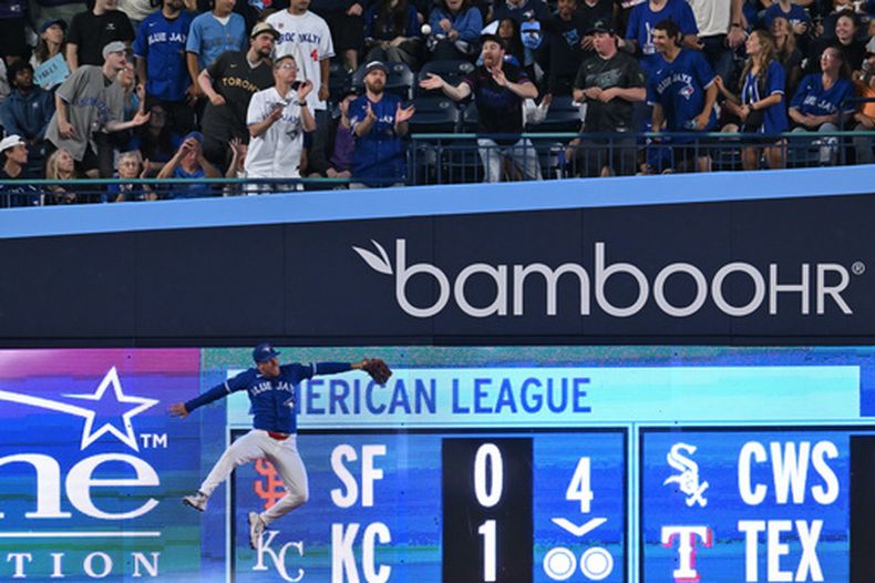 Myles Straw, de los Azulejos de Toronto, intenta infructuosamente atrapar una bola que se fue de jonrón en el duelo ante los Rays de Tampa Bay, el martes 21 de julio de 2026 (Jon Blacker/The Canadian Press via AP)