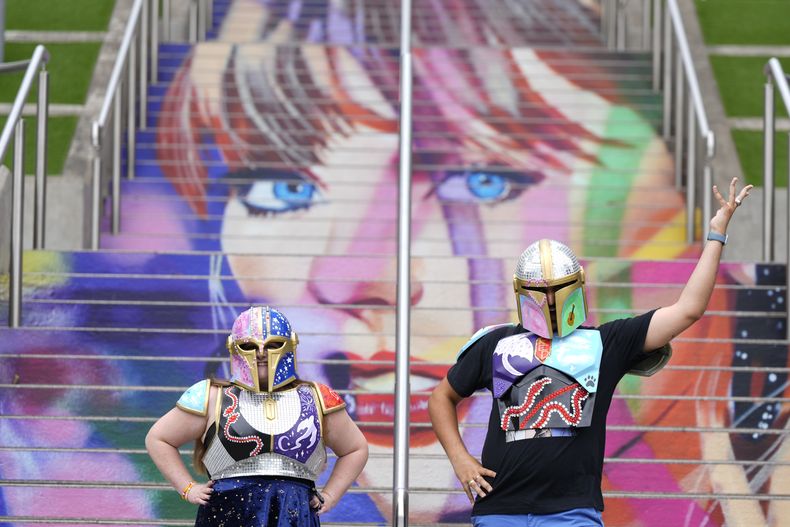 Kristina Broclebanl, izquierda y Max Avatar Barnett, fans de Taylor Swift, posan junto a un retrato de Swift pintado en una escalera en el estadio de Wembley en Londres, el miércoles 14 de agosto de 2024, antes de una serie de conciertos de Taylor Swift que comienzan el jueves. (Foto AP/Alastair Grant)