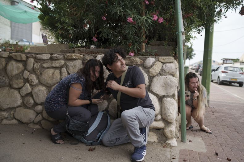 Israelíes se ponen a cubierto ante los proyectiles disparados desde la Franja de Gaza, en Ashkelon, en el sur de Israel, el 11 de octubre de 2023. (AP Foto/Leo Correa)