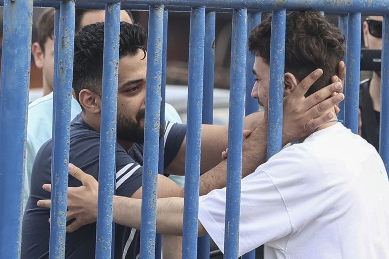 Fedi (derecha), un sirio de 18 años que estaba entre los 104 sobrevivientes del naufragio de un pesquero atestado de migrantes en el Mar Egeo, se alegra al ver a su hermano Mohammad, quien viajó desde Italia para encontrarse con él, el viernes 16 de junio de 2023, en el puerto de Kalamata, Grecia. (John Liakos/InTime News vía AP)