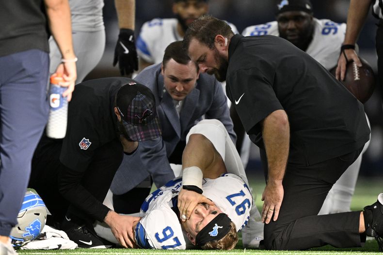 Aidan Hutchinson (97), defensive end de los Lions de Detroit, es atendido por el personal médico del equipo después de sufrir una lesión, aparentemente una fractura, durante la segunda mitad del juego de la NFL en contra de los Cowboys de Dallas, el domingo 13 de octubre de 2024, en Arlington, Texas. (AP Foto/Jerome Miron)