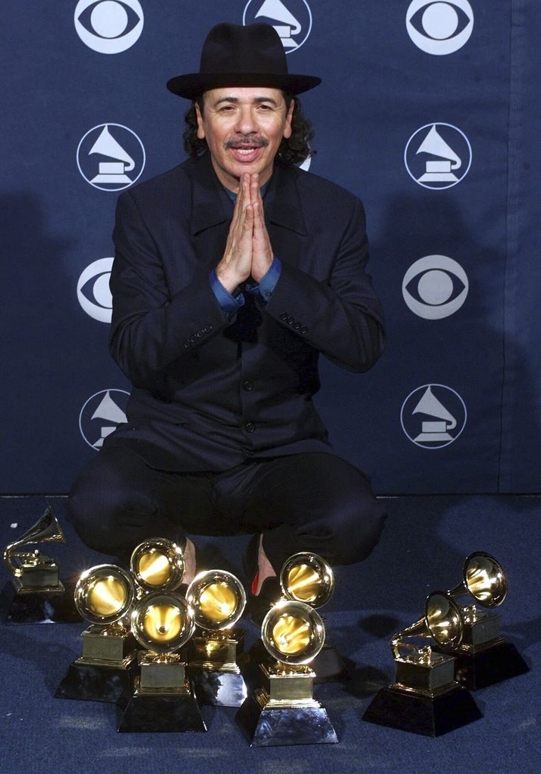 ARCHIVO - Carlos Santana posa con sus premios Grammy en la 42a entrega anual de los Premios Grammy en Los Angeles el 23 de febrero del 2000. El documental Carlos presenta la vida y la obra del artista. (Foto AP/Reed Saxon, archivo)