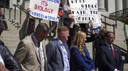Legisladores escuchan a padres de familia que hablan sobre la posibilidad de que sus hijos compitan contra niñas transgénero en competencias deportivas escolares, el 25 de marzo de 2022 en el Capitolio estatal de Utah, en Salt Lake City. El letrero de la izquierda dice: No es discriminación. Es biología. Equidad en el deporte, y el de la derecha dice: Mantengan los deportes de chicas equitativos para las chicas. (AP Foto/Samuel Metz, Archivo)