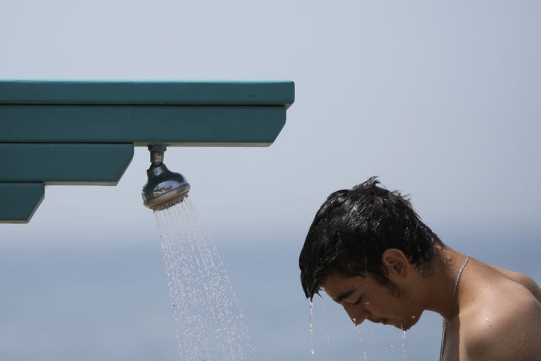 Un hombre se ducha en una regadera pública en la playa de Paleo Faliro, en el sur de Atenas, Grecia, el 23 de junio de 2022. (AP Foto/Thanassis Stavrakis, File)