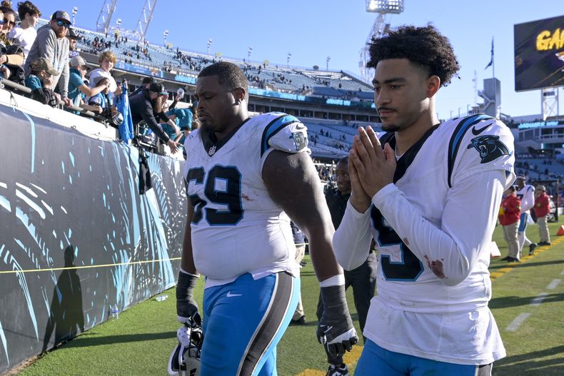 El quarterback de los Panthers de Carolina Bryce Young y el guardia Gabe Jackson salen del terreno luego de la derrota ante los Jaguars de Jacksonville, en un juego de la NFL el domingo 31 de diciembre de 2023, en Jacksonville, Florida. (AP Foto/Phelan M. Ebenhack)