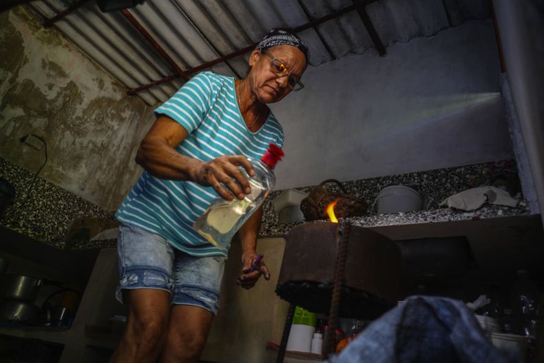 Rosa López enciende un horno a carbón para hervir boniatos y preparar huevos revueltos con tomate para sus nietos en su casa en Mariel, Cuba, el jueves 18 de mayo de 2023. (AP Foto/Ramón Espinosa)