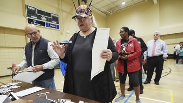 ARCHIVO - Blythe González, a la derecha, hace una pregunta a un trabajador del distrito electoral de Jackson, Mississippi, mientras su marido Jorge González, a la izquierda, espera con su papeleta, para acompañarla a un quiosco de votación, 5 de noviembre de 2024. (AP Rogelio V. Solis, archivo)