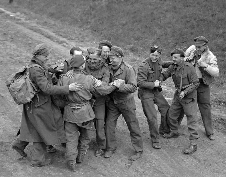 ARCHIVO - Prisioneros británicos liberados poco antes se reúnen con un equipo de paracaidistas mientras marchan hacia líneas aliadas en Alemania, el 4 de mayo de 1945. Las autoridades alemanas habían liberado recientemente a 8.000 prisioneros de guerra británicos. (AP Foto/Eddie Worth, Archivo)